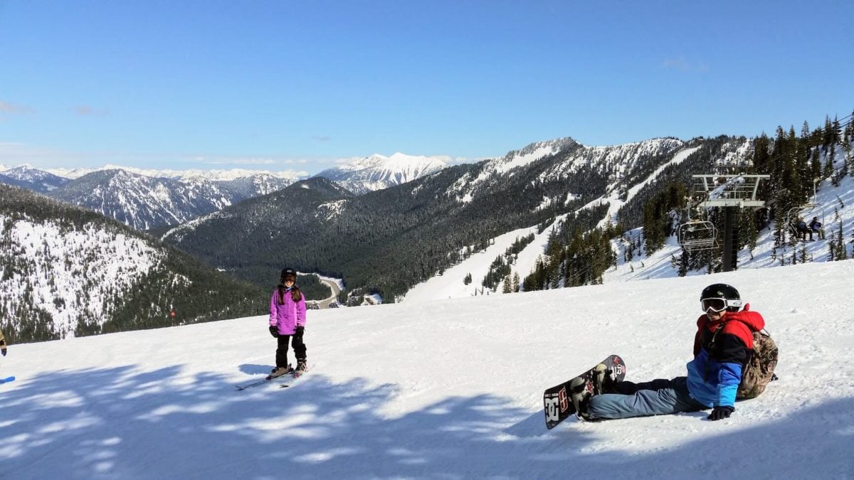 Snowboarder resting on a sunny slope at Stevens Pass