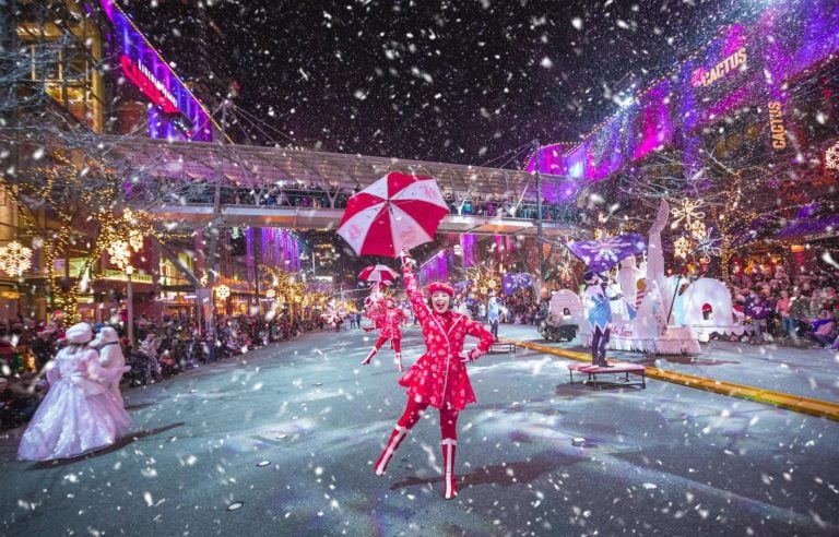 Snowflake Lane performers under falling snow and holiday lights in downtown Bellevue