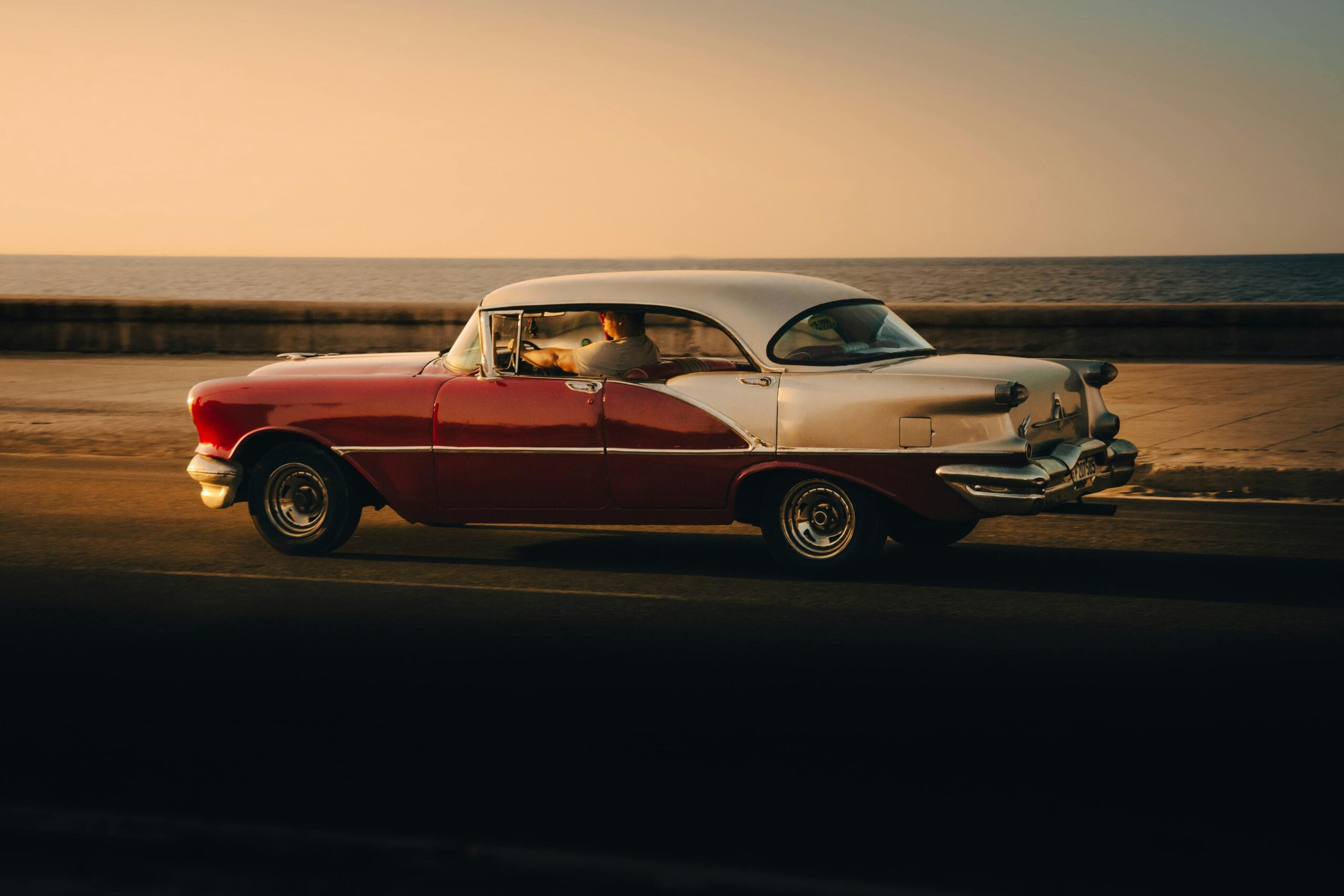Vintage classic car cruising by the seaside at sunset