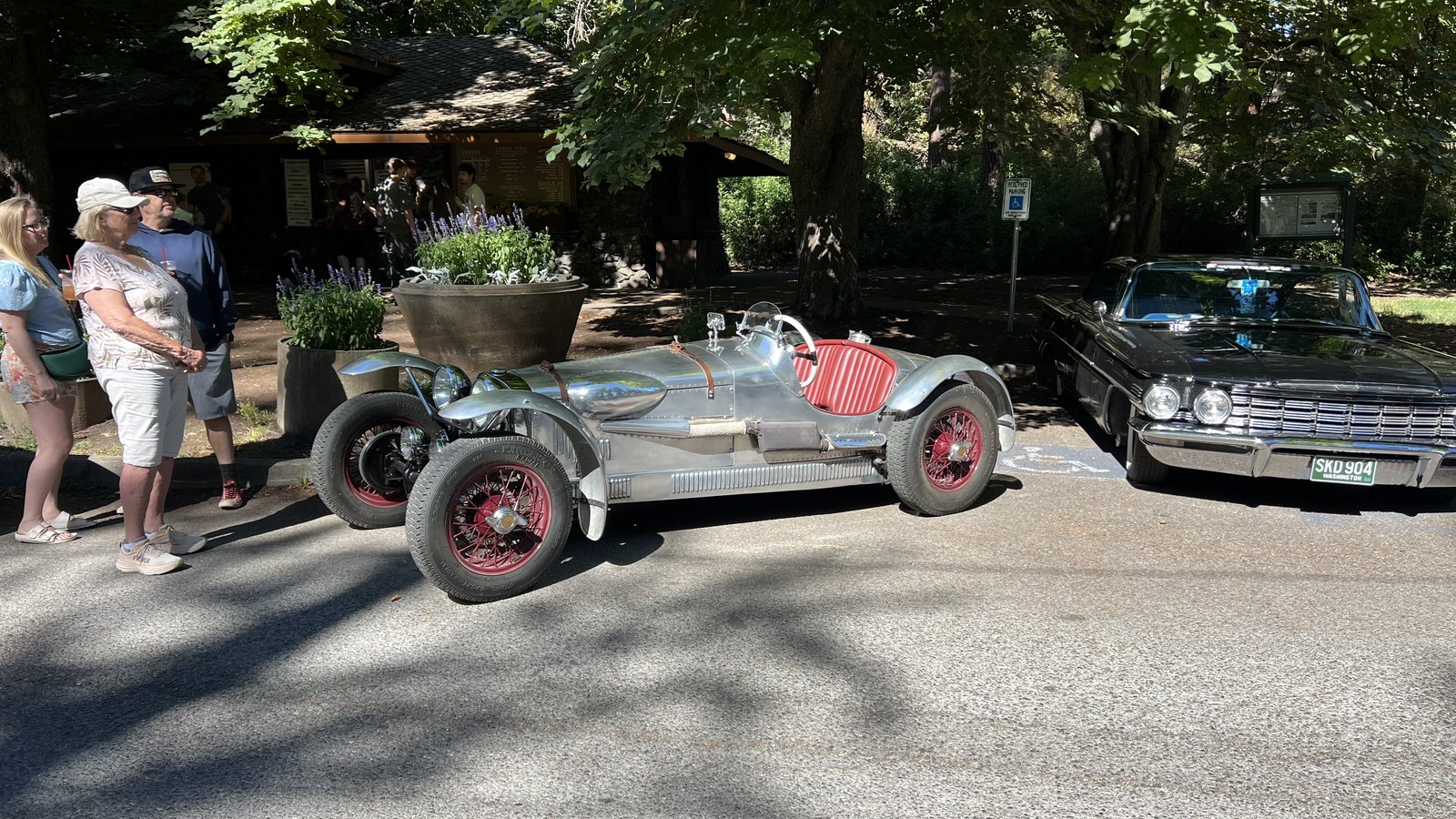 Polished aluminum speedster on red wire wheels parked outside the Park Bench Cafe during the monthly Cars and Coffee at Manito Park in Spokane
