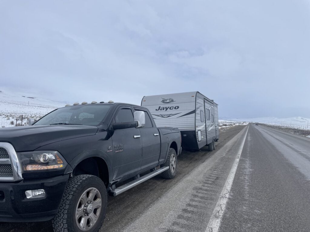 Pickup truck towing a Jayco travel trailer on a snowy highway