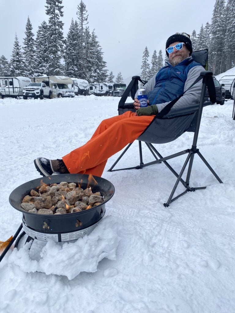 Relaxing beside a propane fire pit at a snowy RV campground