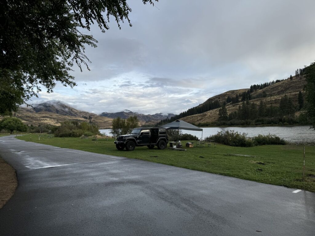 A truck and canopy at a lakeside campsite at Pearrygin Lake State Park, with mist over the hills behind