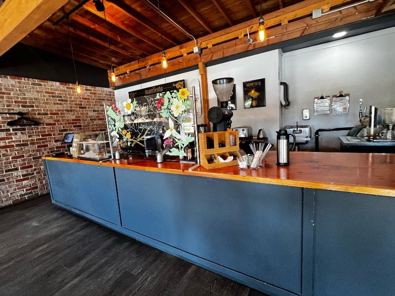 The long wood topped counter, brick wall and exposed beam ceiling inside Manifesto Coffee on South 11th Street in Tacoma