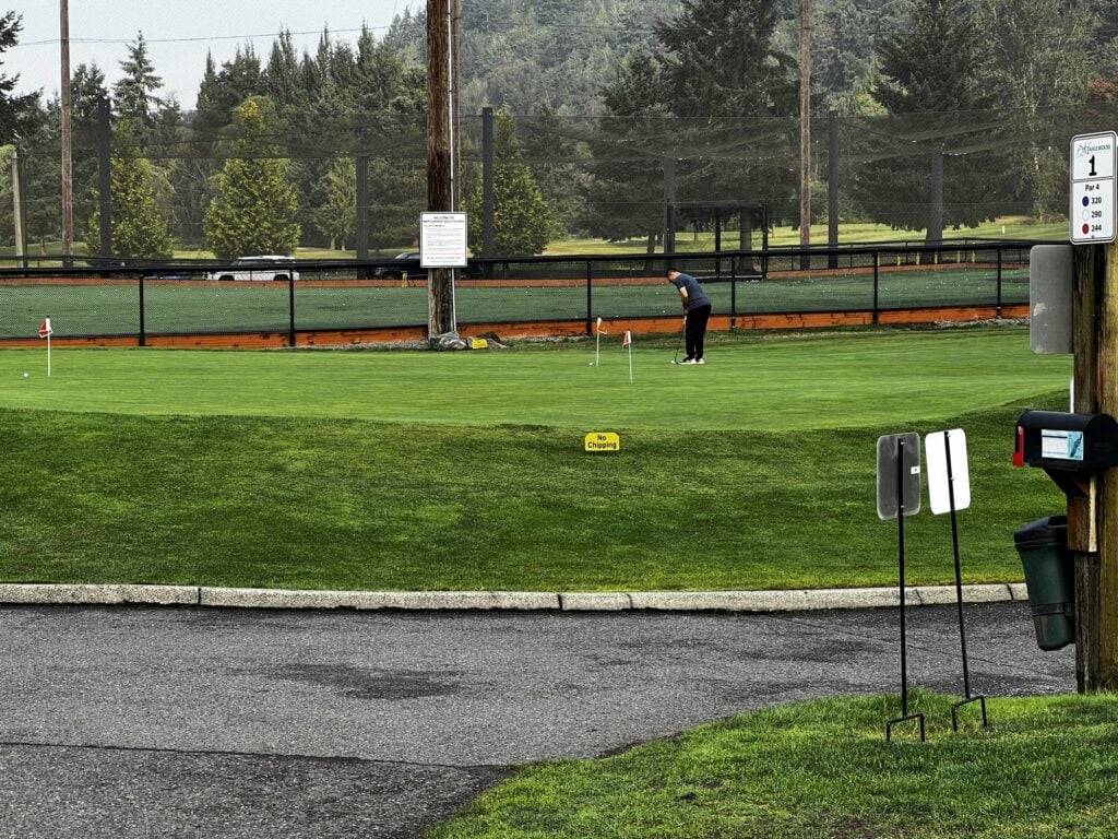 The practice area at Maplewood Golf Course with the driving range netting behind