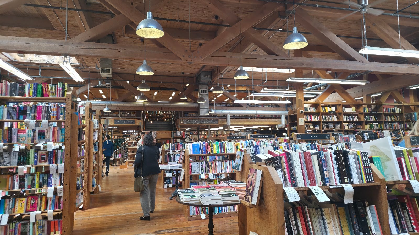 Long aisles of wooden shelves under the timber beams of Elliott Bay Book Company on Capitol Hill