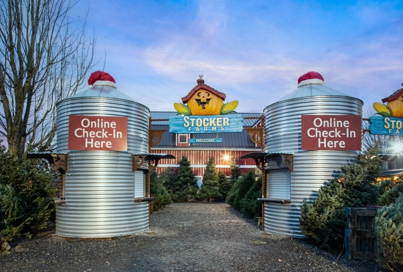 Stocker Farms entrance in Snohomish, with two silos wearing Santa hats and online check in signs in front of the red barn