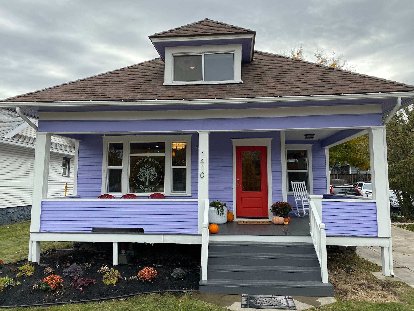 The purple house that holds Wishing Tree Books, with a red door and a front porch